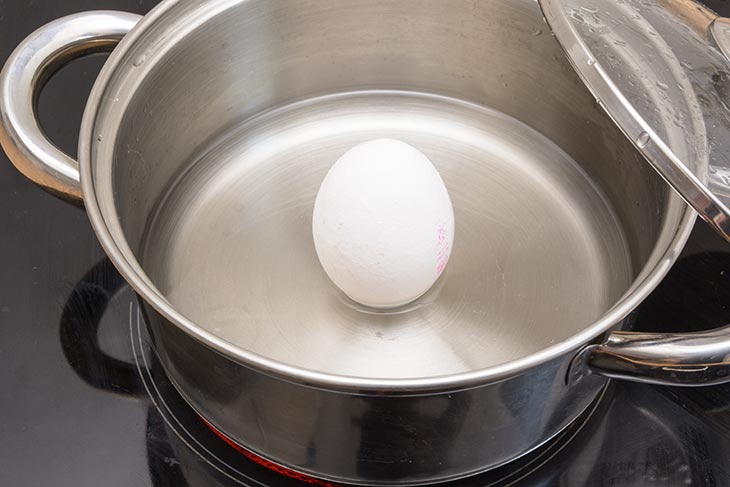Ein Ei steht aufrecht in einem Topf.